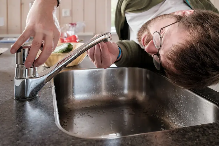 Tecnico che ispeziona il rubinetto di una cucina luminosa